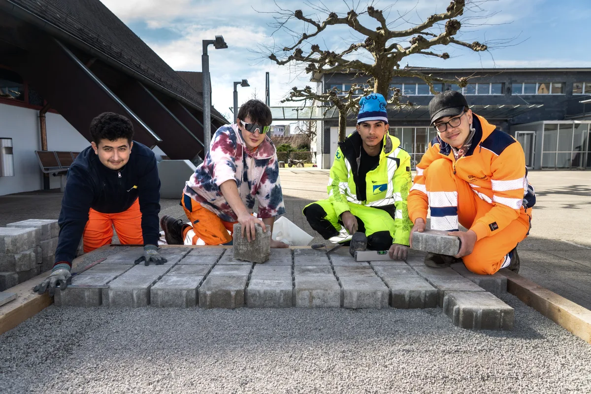 Von links: Denis, Alex, David und Ruben arbeiten am Übungsrahmen. Teamleiter David zeigt den Lernenden, wie es funktioniert. Stadt Wetzikon und Strassenbaufirma Inauen zeigen 30 Lernenden, wie Pflastersteine verlegt werden.